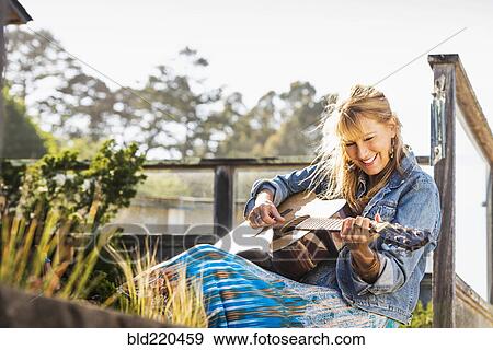 Caucasian woman playing guitar on porch View Large Photo Image Stock Photo - Caucasian woman playing guitar on porch. Fotosearch