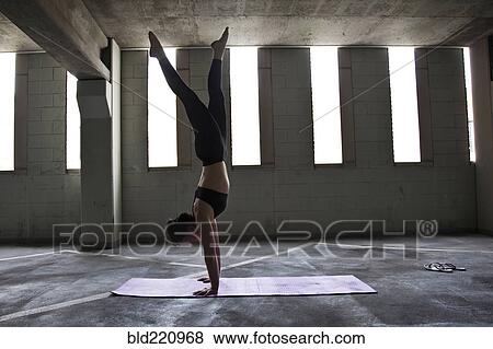 Stock Photo - Caucasian woman practicing yoga in parking lot. Fotosearch