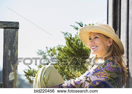 Stock Photograph - Caucasian woman relaxing on porch. Fotosearch