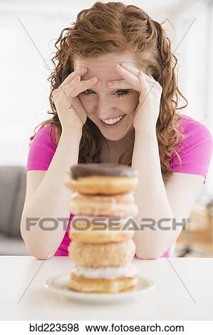 Stock Photo - Caucasian woman resisting pile of donuts on plate. Fotosearch