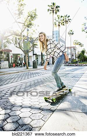 Stock Photo - Caucasian woman riding skateboard. Fotosearch