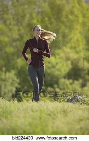 Stock Image - Caucasian woman running on hill. Fotosearch