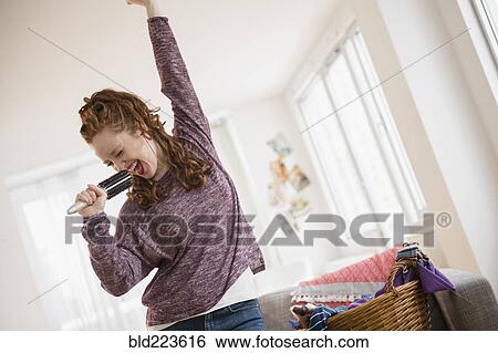 Stock Photograph - Caucasian woman singing with hairbrush microphone. Fotosearch