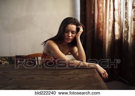 Stock Image - Caucasian woman sitting at table. Fotosearch