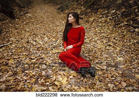 Stock Photo - Caucasian woman sitting in autumn leaves. Fotosearch
