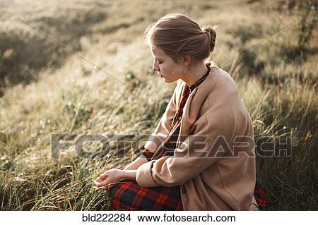 Caucasian woman sitting in remote field View Large Photo Image Picture - Caucasian woman sitting in remote field. Fotosearch