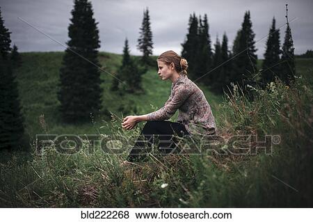 Stock Photo - Caucasian woman sitting in remote field. Fotosearch