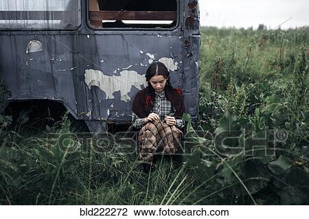 Stock Image - Caucasian woman sitting near antique truck. Fotosearch