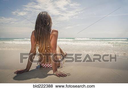 Stock Photo - Caucasian woman sitting on beach. Fotosearch