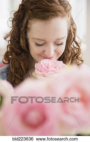 Stock Photograph - Caucasian woman smelling pink rose. Fotosearch