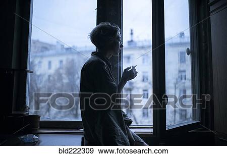 Caucasian woman smoking at open window View Large Photo Image Stock Photo - Caucasian woman smoking at open window. Fotosearch