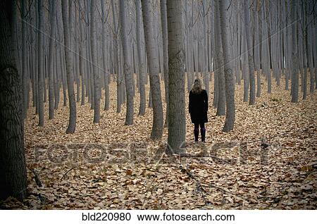 Stock Image - Caucasian woman standing in autumn forest. Fotosearch