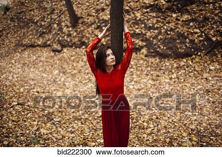 Stock Image - Caucasian woman standing in autumn leaves. Fotosearch