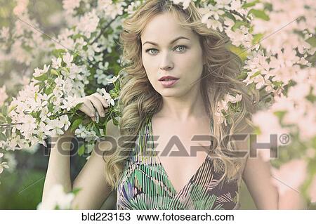 Stock Image - Caucasian woman standing in flowering tree. Fotosearch