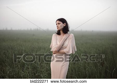 Stock Image - Caucasian woman standing in remote field. Fotosearch