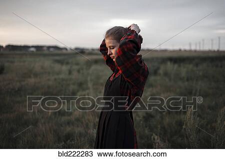 Stock Image - Caucasian woman standing in remote field. Fotosearch