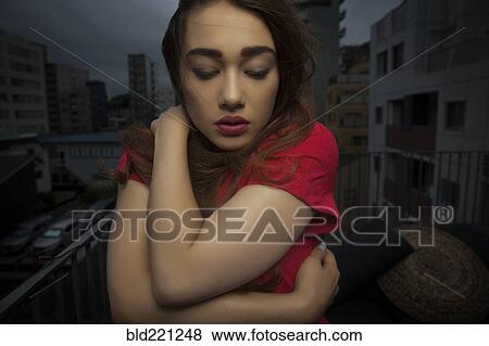 Stock Photo - Caucasian woman standing on balcony. Fotosearch