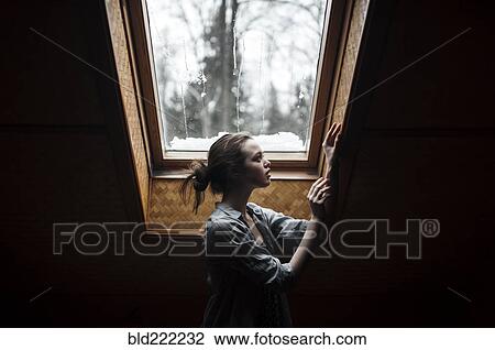 Stock Image - Caucasian woman standing under skylight. Fotosearch