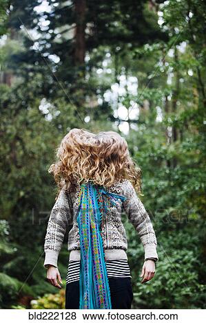 Stock Photo - Caucasian woman tossing hair in forest. Fotosearch