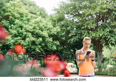 Caucasian woman using cell phone and earbuds outdoors View Large Photo Image Stock Image - Caucasian woman using cell phone and earbuds outdoors. Fotosearch