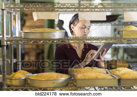 Caucasian woman using digital tablet in bakery View Large Photo Image Stock Photo - Caucasian woman using digital tablet in bakery. Fotosearch