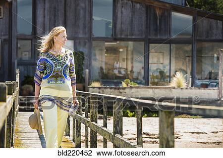 Stock Image - Caucasian woman walking on wooden walkway. Fotosearch