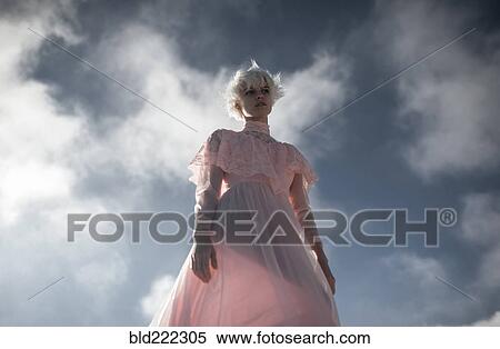 Stock Photography - Caucasian woman walking under cloudy sky. Fotosearch