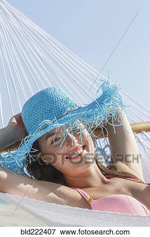 Stock Photo - Caucasian woman wearing sun hat in hammock. Fotosearch