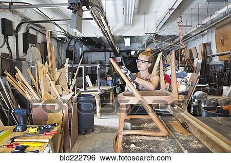 Caucasian woman working on wooden chair in workshop View Large Photo Image Stock Photograph - Caucasian woman working on wooden chair in workshop. Fotosearch