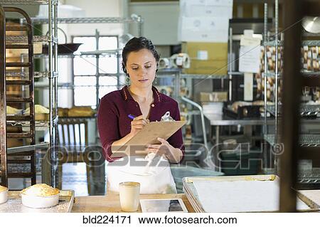 Caucasian woman writing on clipboard in bakery View Large Photo Image Stock Image - Caucasian woman writing on clipboard in bakery. Fotosearch