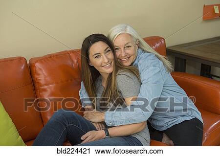 Stock Image - Caucasian women hugging on sofa. Fotosearch