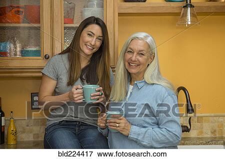 Caucasian women posing in kitchen drinking coffee View Large Photo Image Stock Photo - Caucasian women posing in kitchen drinking coffee. Fotosearch