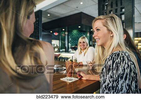 Stock Photo - Caucasian women sitting at bar with cocktails. Fotosearch