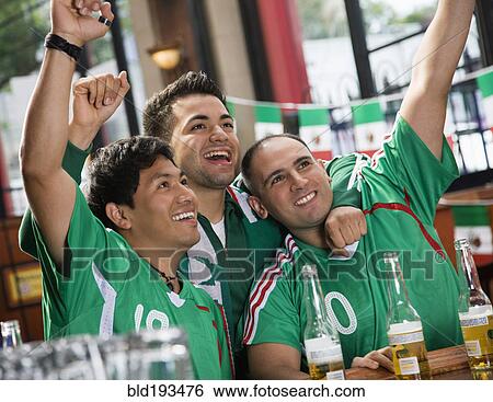 Cheering Hispanic men watching television in sports bar View Large Photo Image Stock Photograph - Cheering Hispanic men watching television in sports bar. Fotosearch