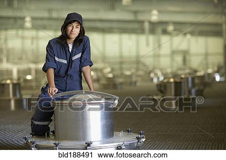 Stock Image - Chilean woman standing near vat at winery. Fotosearch