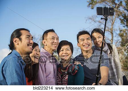 Picture - Chinese family taking photograph with selfie stick. Fotosearch