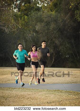 Stock Image - Chinese friends jogging in park. Fotosearch