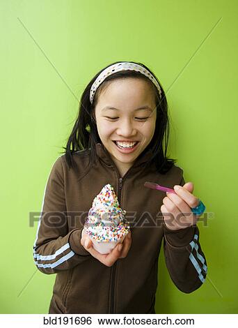 Stock Photograph - Chinese girl eating ice cream with sprinkles. Fotosearch