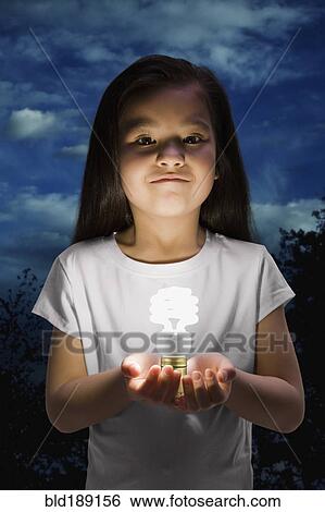Stock Photograph - Chinese girl holding glowing cfl lightbulb. Fotosearch