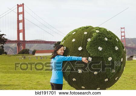 Stock Image - Chinese girl hugging earth topiary. Fotosearch