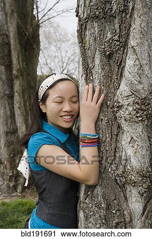 Stock Image - Chinese girl hugging tree. Fotosearch