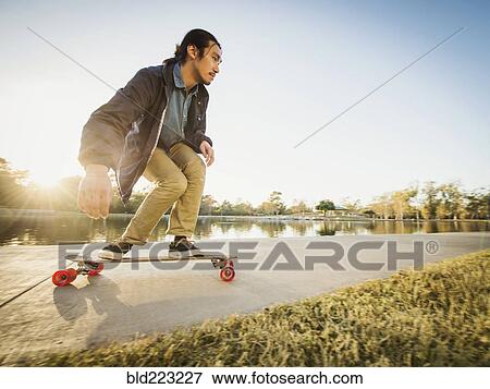 Stock Photo - Chinese man skateboarding in park. Fotosearch
