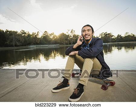 Stock Photo - Chinese man talking on cell phone in park. Fotosearch