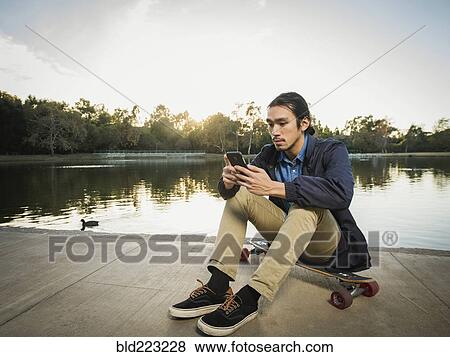 Stock Photo - Chinese man using cell phone in park. Fotosearch