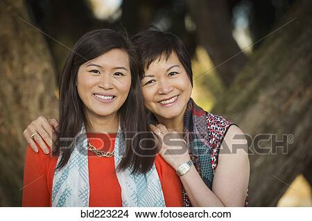 Picture - Chinese mother and daughter hugging outdoors. Fotosearch