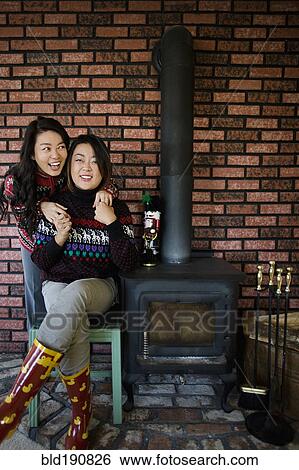 Stock Photograph - Chinese mother and daughter hugging near fireplace. Fotosearch