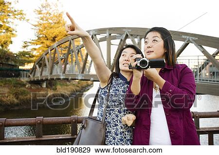 Stock Photo - Chinese mother and daughter taking photographs outdoors. Fotosearch