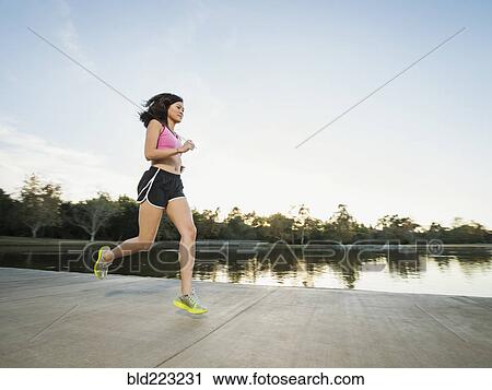 Stock Image - Chinese woman jogging in park. Fotosearch