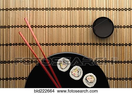 Picture - Chopsticks and sushi on round plate with dipping sauce. Fotosearch