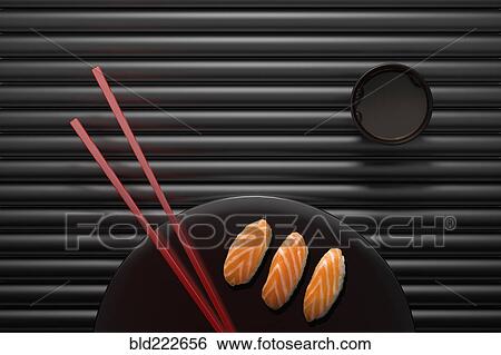 Stock Photograph - Chopsticks and sushi on round plate with dipping sauce. Fotosearch
